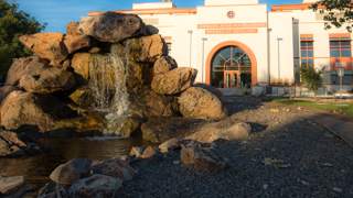 Image of the front of the Bureau of Mining and a pond and waterfall in the foreground